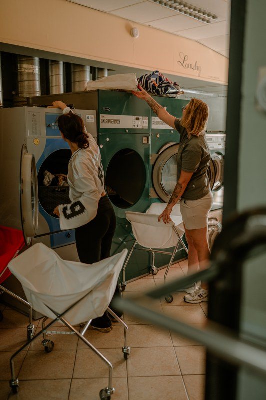 Twee mensen verzorgen was bij de wasmachines van Het Wasmandje.